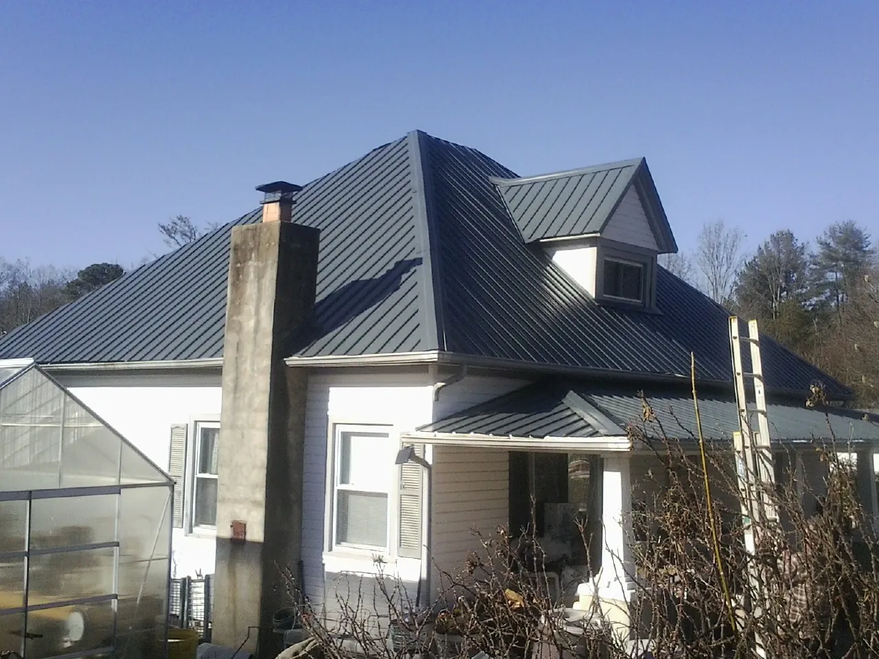 Dark blue standing seam metal roof on a white farmhouse with dormer — Slate & Tile Roof Repair by Roofing Brothers in Orefield