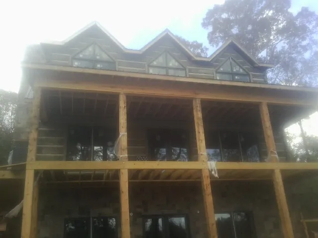 Dormers and porch framing on a large log home under construction — Roof Coating work by our crew in Orefield