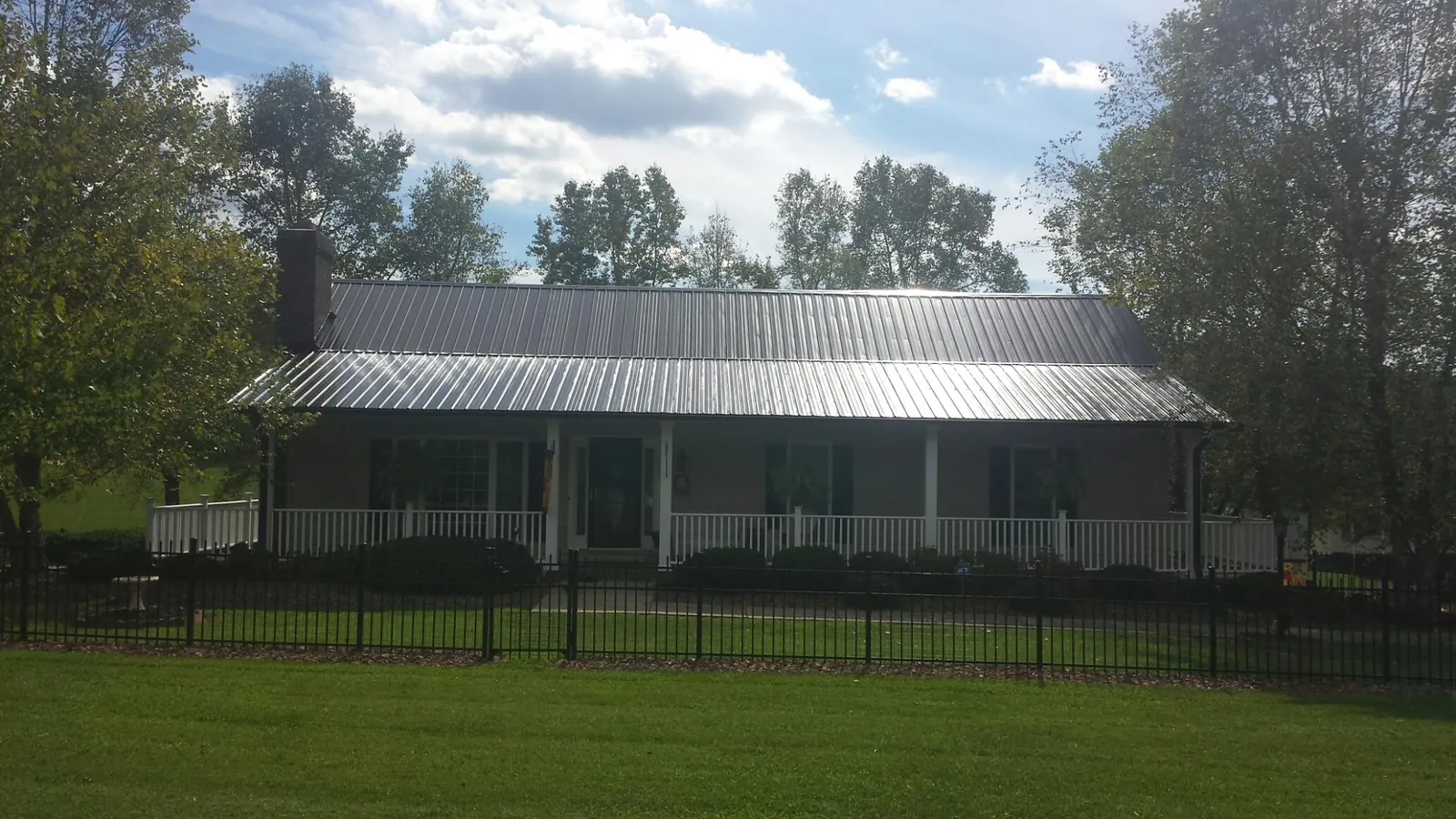 Gray metal roof on a brick ranch with a full width front porch — Gutter Guard Installation work by our crew in Orefield