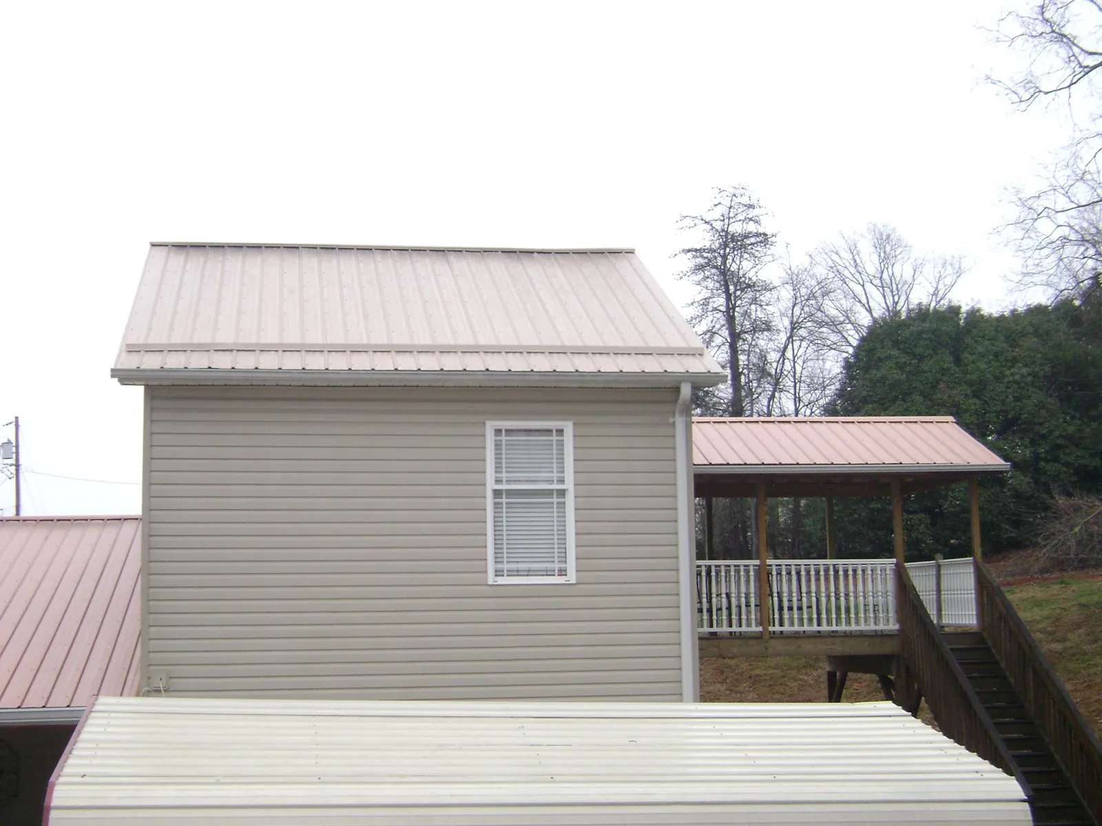 Tan metal roofs on a two story addition and attached porch, from a Roof Replacement job in Orefield
