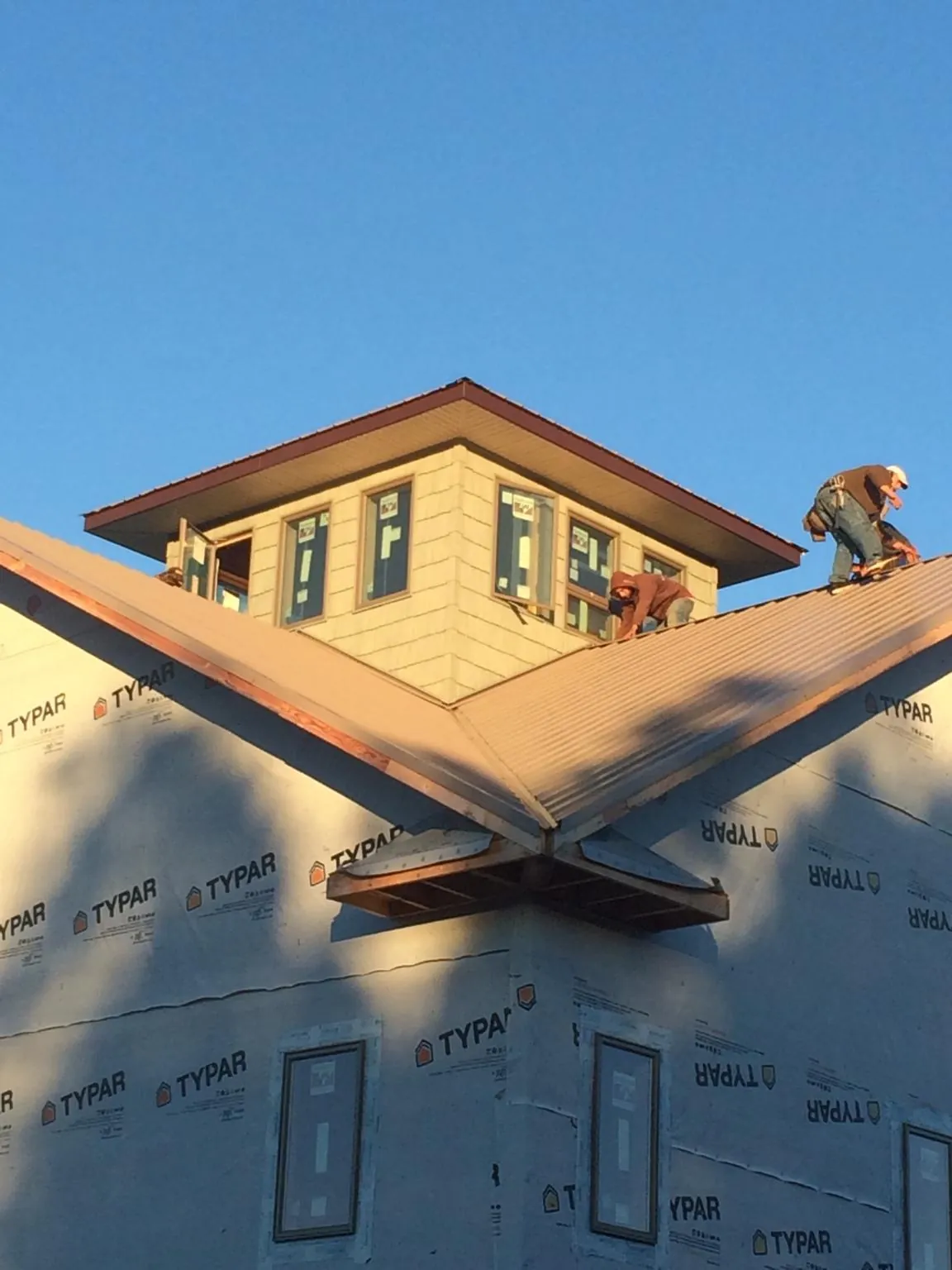 Roofers working around a rooftop cupola on a new metal roof at sunset — Roof Waterproofing in Orefield by Roofing Brothers